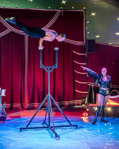 Akrobat führt eine beeindruckende Übung an einem vertikalen Gerät im Zirkus auf.